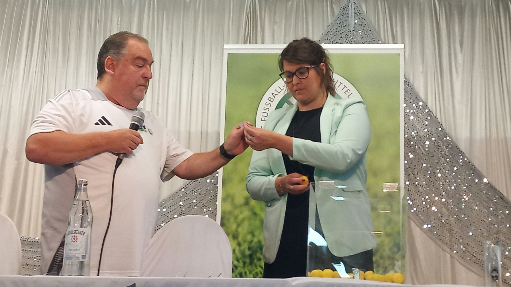 Eine Frau und ein Mann ziehen Lose aus einer Box