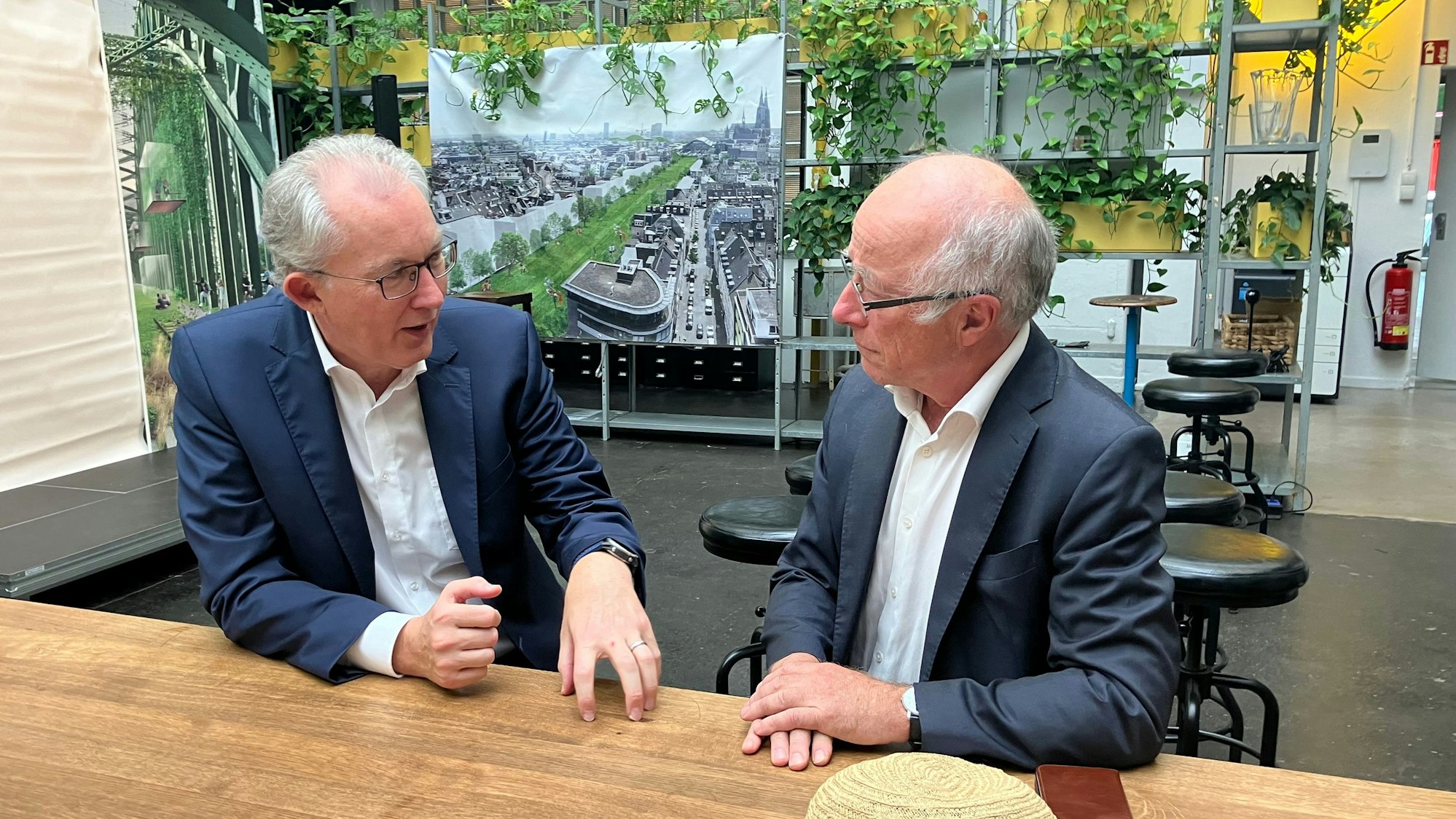 Ulrich Voigt, Vorstandsvorsitzender der Sparkasse Köln-Bonn (links) und Architekt Paul Böhm sitzen an einem Tisch und sprechen über ihre Visionen für Köln.
