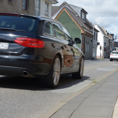 Die Ortsdurchfahrt in Euskirchen-Kuchenheim wird von mehreren Autos in Blickrichtung der Kamera befahren.