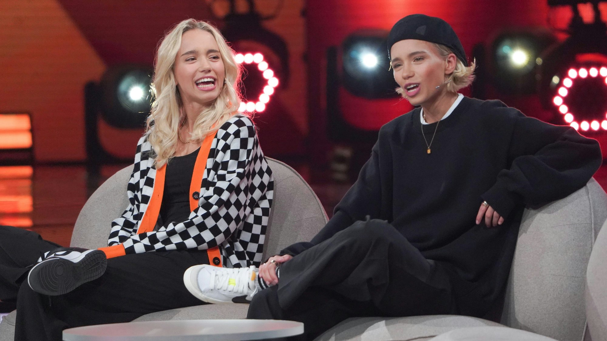Die Zwillinge Lisa (l.) und Lena sitzen auf einer Couch bei der ARD-Show „Verstehen sie Spaß?“.