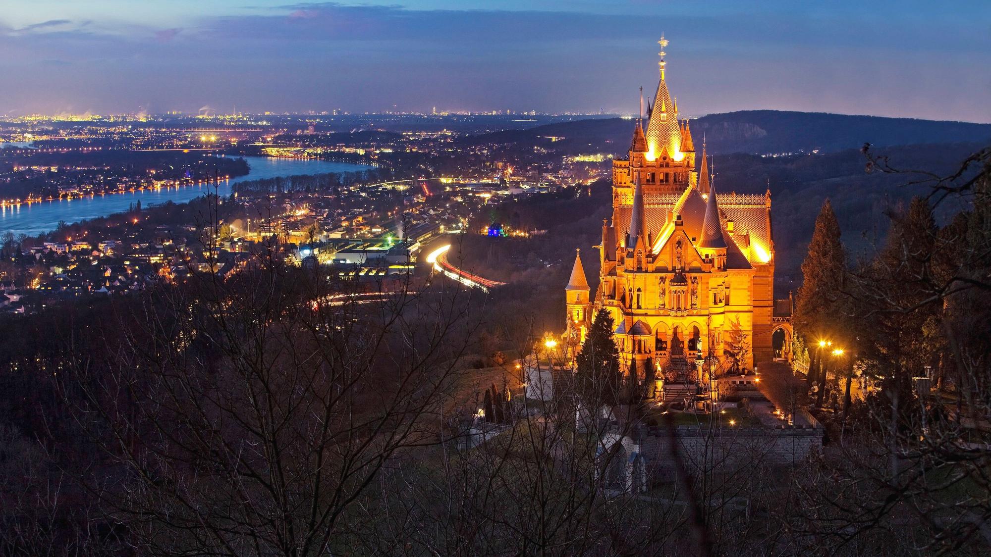 Beleuchtetes Schloss Drachenburg über dem Rheintal am Abend.