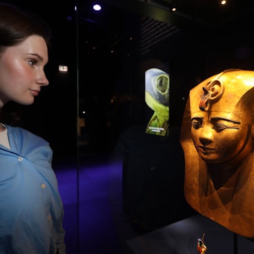 Eine Frau betrachtet eine Holzmaske