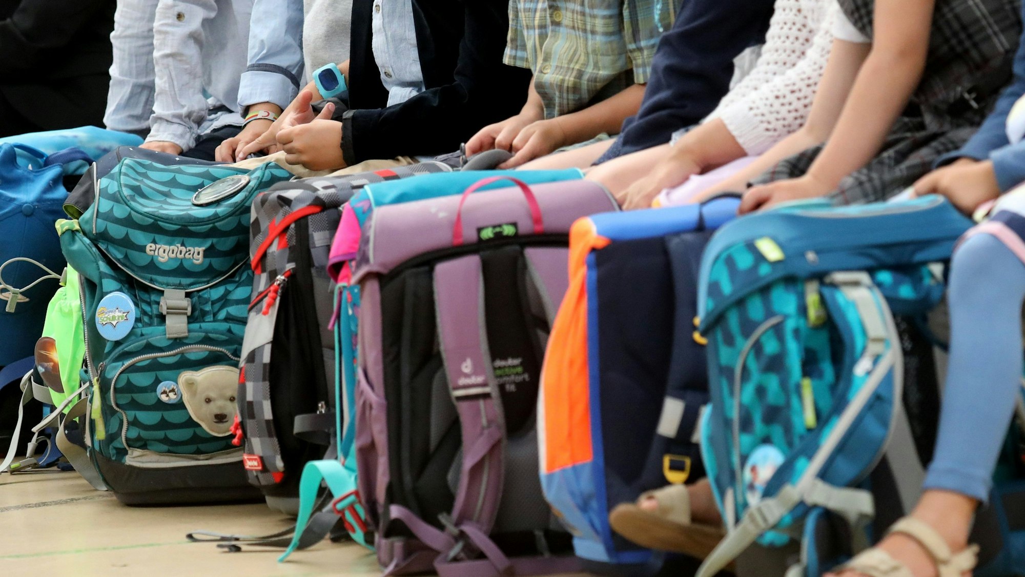 Kinder mit Schulranzen auf der Bank.