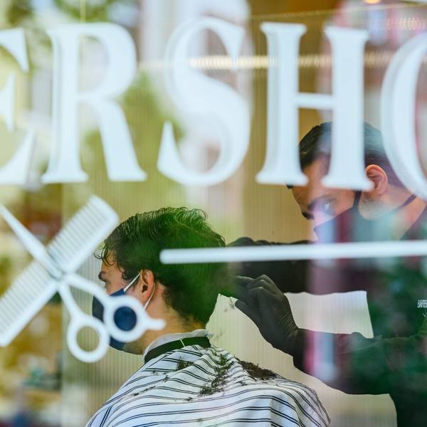 Ein Friseur schneidet in einm Barbershop einem Kunden die Haare.