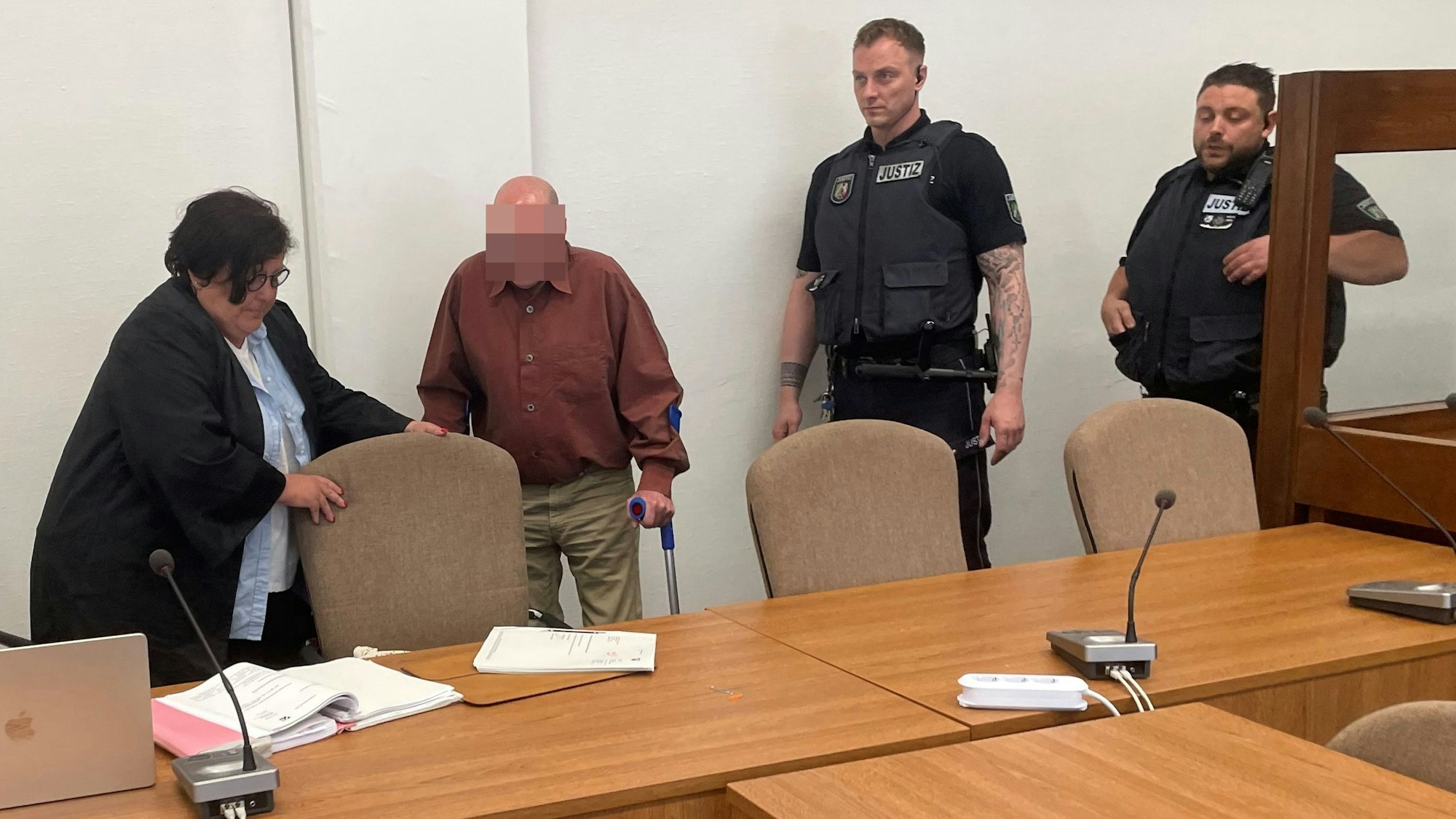 Der Angeklagte mit Verteidigerin Karin Bölter und zwei Wachtmeistern beim Prozessauftakt im Kölner Landgericht