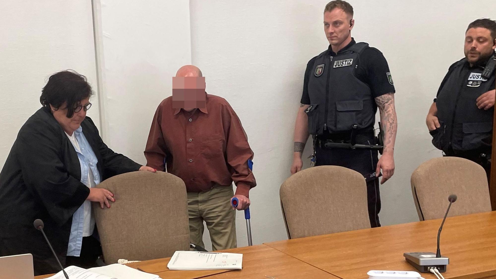 Der Angeklagte mit Verteidigerin Karin Bölter und zwei Wachtmeistern beim Prozessauftakt im Kölner Landgericht