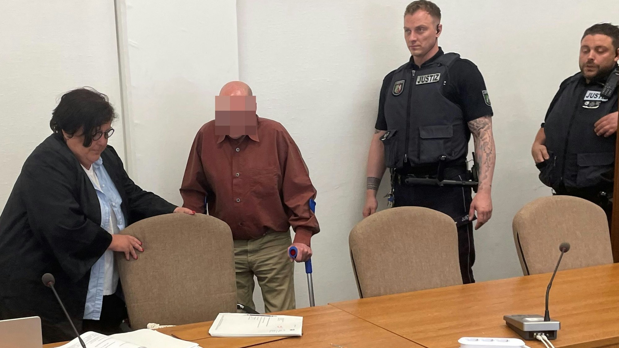 Der Angeklagte mit Verteidigerin Karin Bölter und zwei Wachtmeistern beim Prozessauftakt im Kölner Landgericht