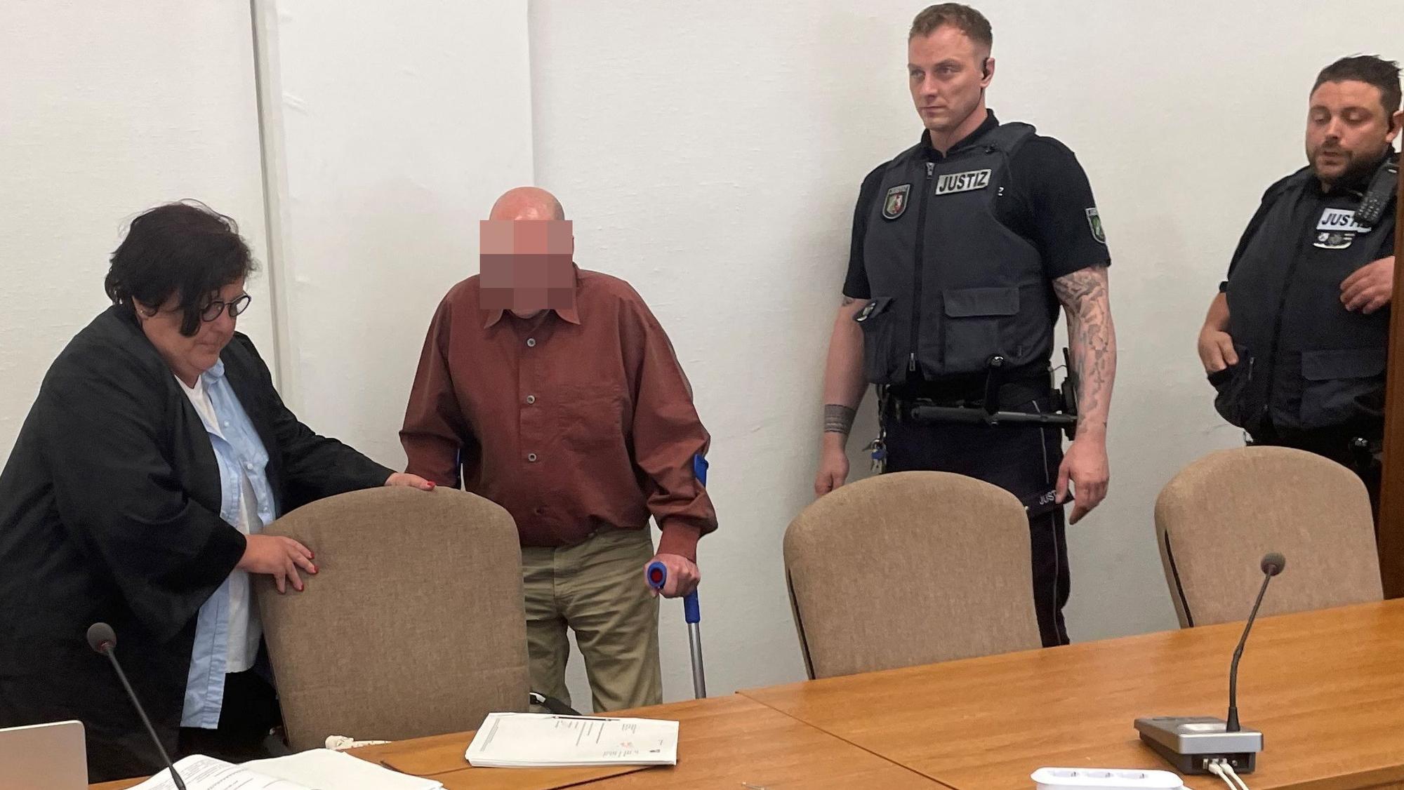 Der Angeklagte mit Verteidigerin Karin Bölter und zwei Wachtmeistern beim Prozessauftakt im Kölner Landgericht