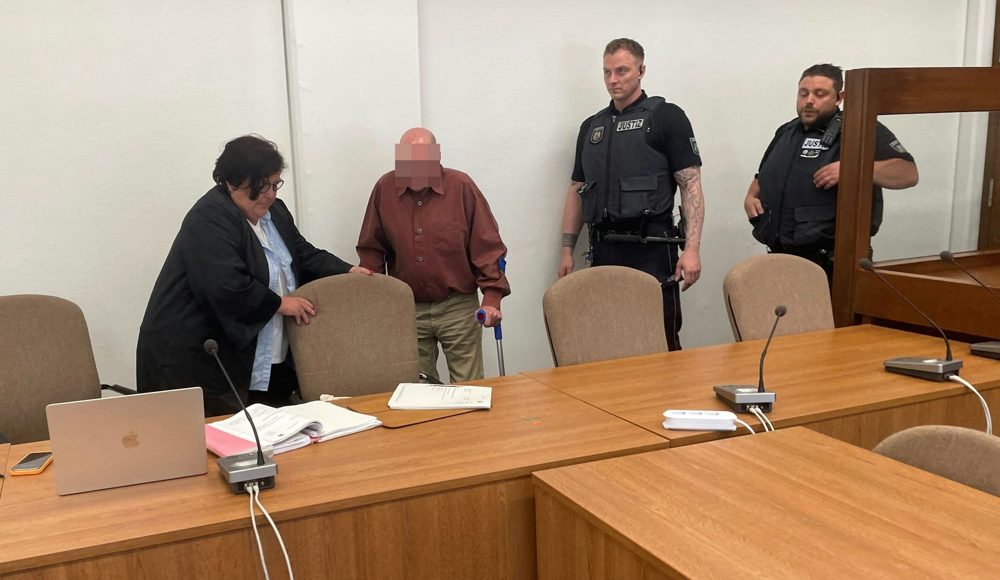 Der Angeklagte mit Verteidigerin Karin Bölter und zwei Wachtmeistern beim Prozessauftakt im Kölner Landgericht