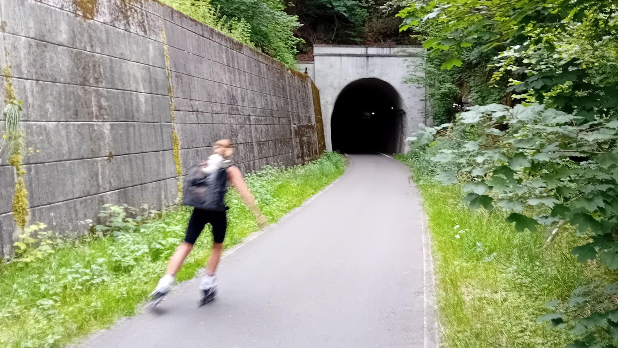 Eine Rollschuhläufer fährt in einen Tunnel ein.