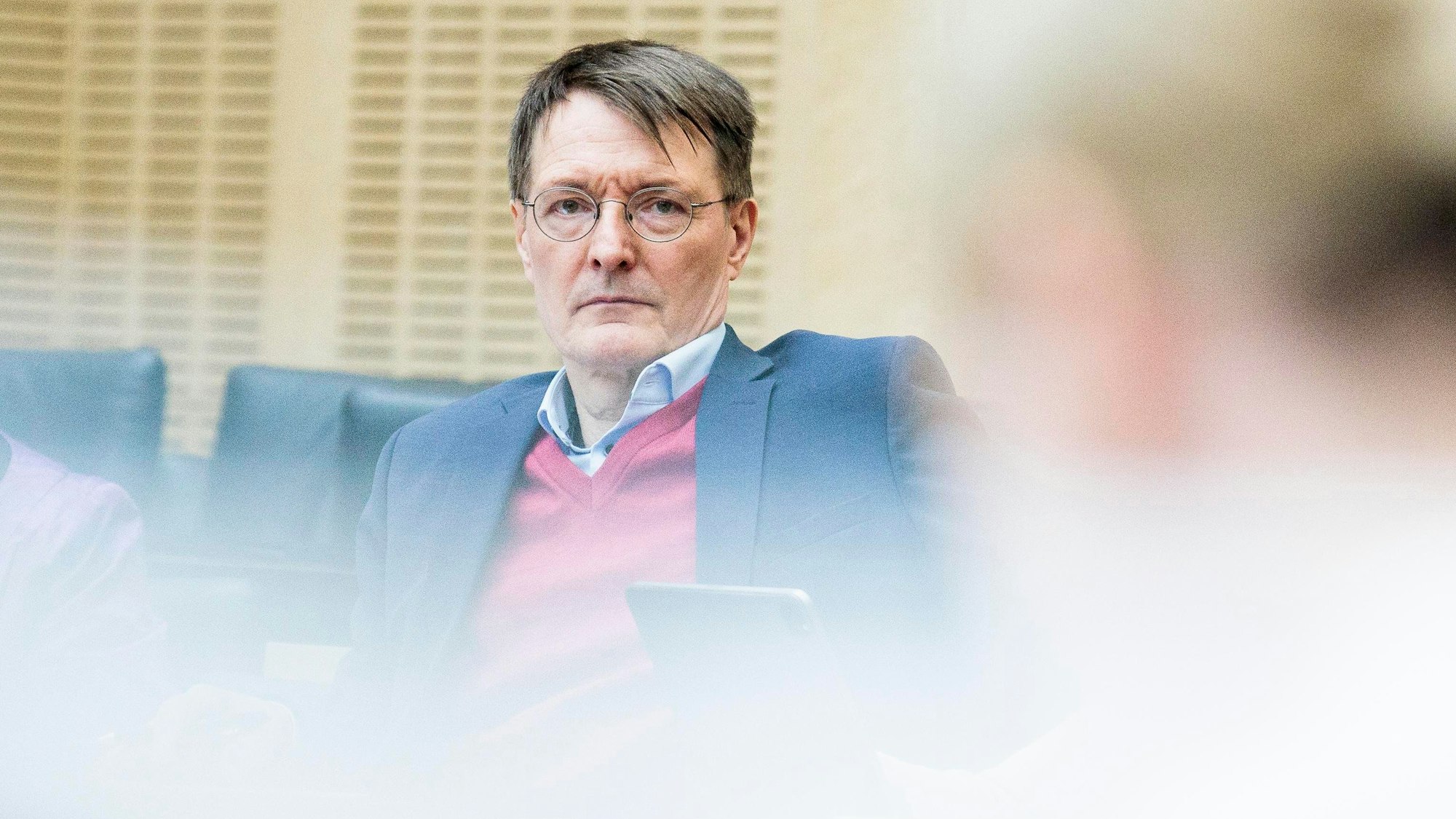 Bundesgesundheitsminister Karl Lauterbach (SPD) sitzt während eines Meetings an einem Tisch und blickt in die Kamera.