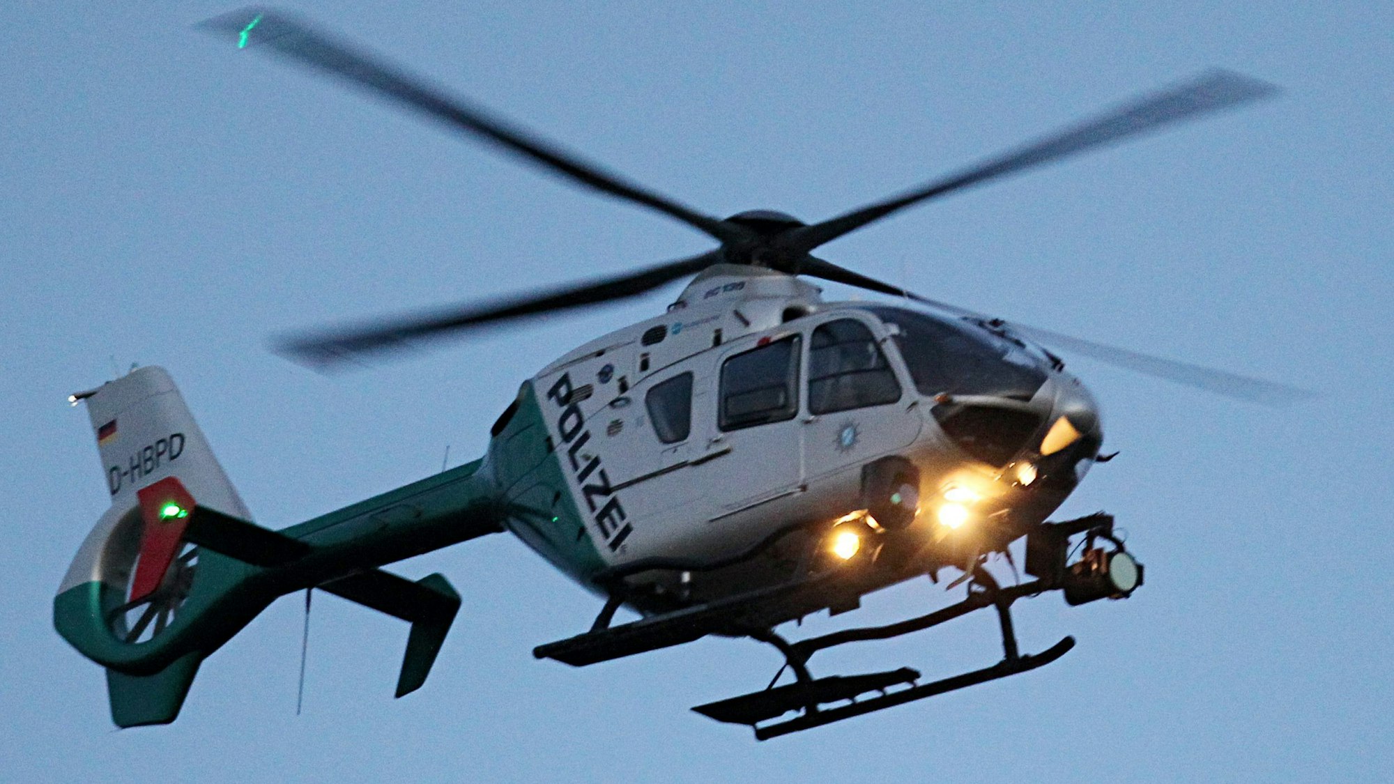 Ein Polizeihubschrauber mit eingeschalteten Scheinwerfern.