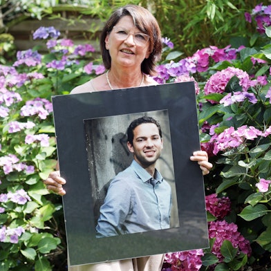 Bernadette Rüggeberg zeigt ein großes Porträt ihres Sohnes, im Hintergrund blühende Hortensien