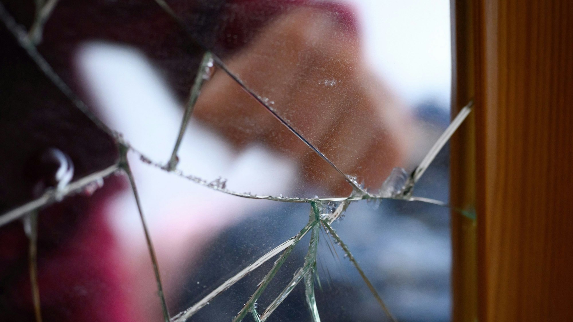 Eine Faust ist auf einem gesprungenen Spiegel zu sehen.