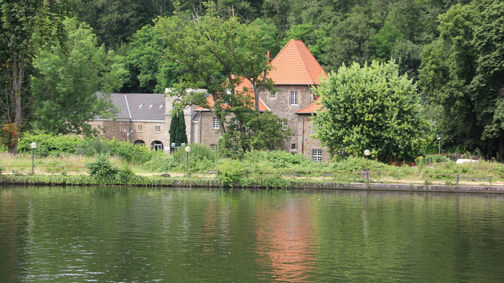 Ein kleines Schloss am Ufer des Baldenysees spiegelt sich im Wasser.
