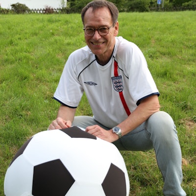 Ein Mann in einem Trikot der englischen Nationalmannschaft mit einem überdimensionalen Fußball