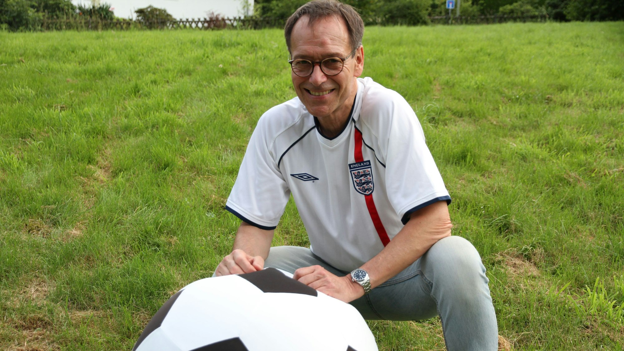 Ein Mann in einem Trikot der englischen Nationalmannschaft mit einem überdimensionalen Fußball