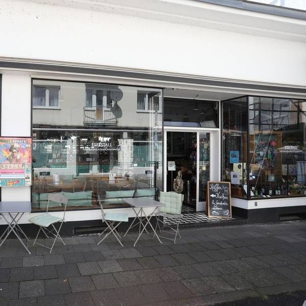 Ein kleines Lokal mit einer großen Fensterfront und Stühlen auf dem Gehweg.