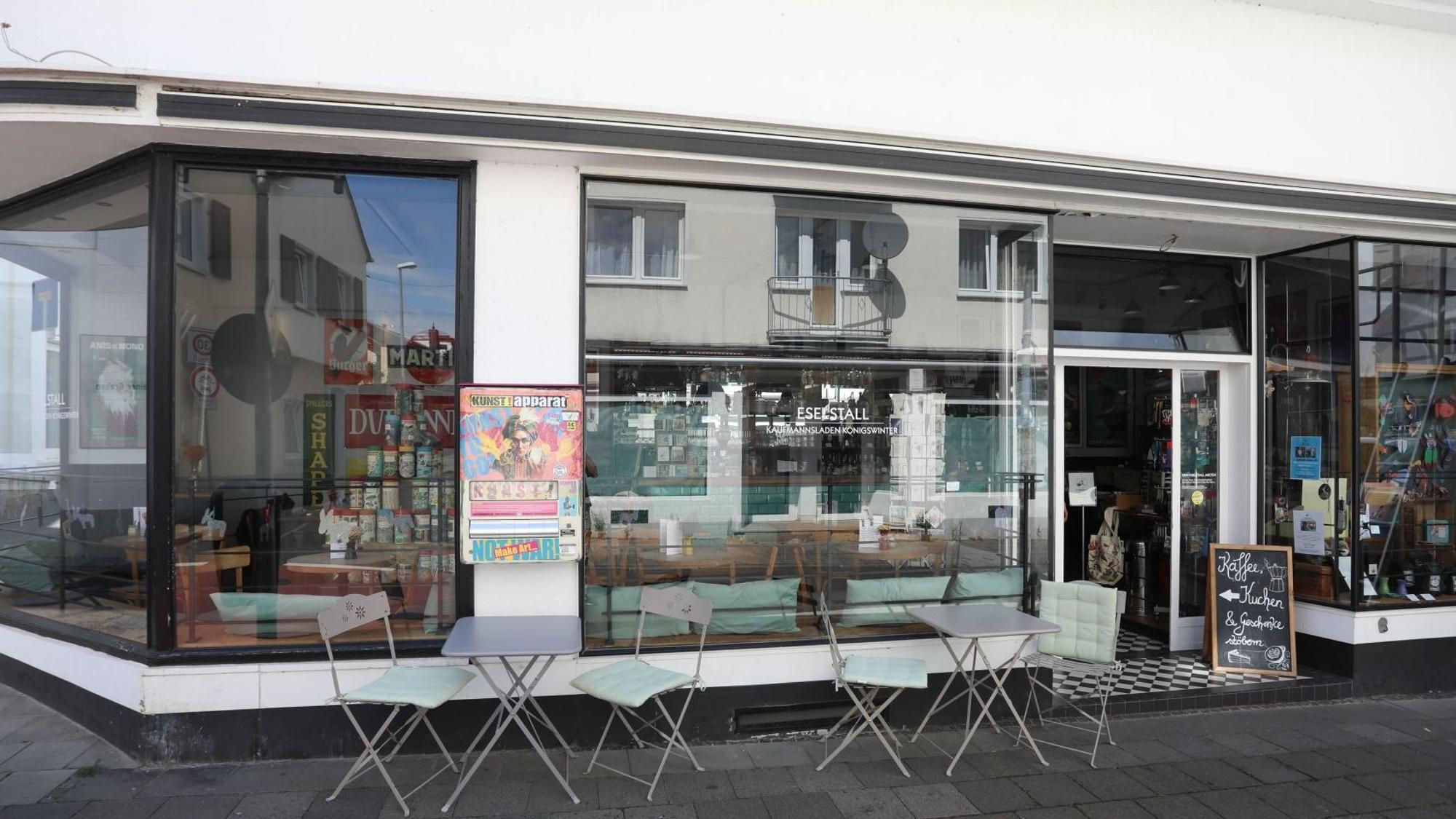 Ein kleines Lokal mit einer großen Fensterfront und Stühlen auf dem Gehweg.