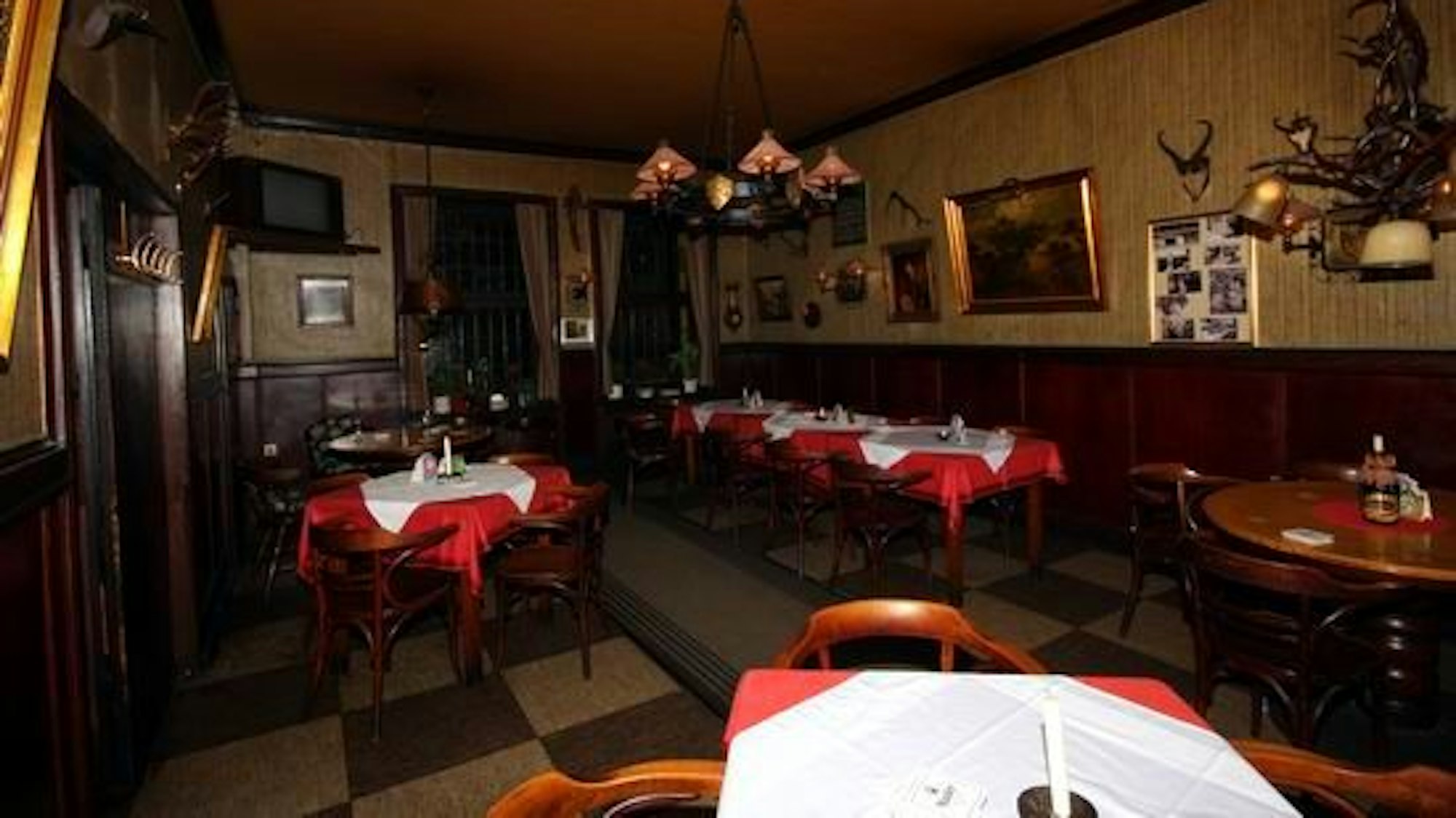 Innenansicht einer historischen Gaststätte mit schwarz-weiß kariertem Fußboden.