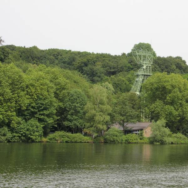 Inmitten von Bäumen steht ein stillgelegter Förderturm am Ufer des Essener Baldeneysess.
