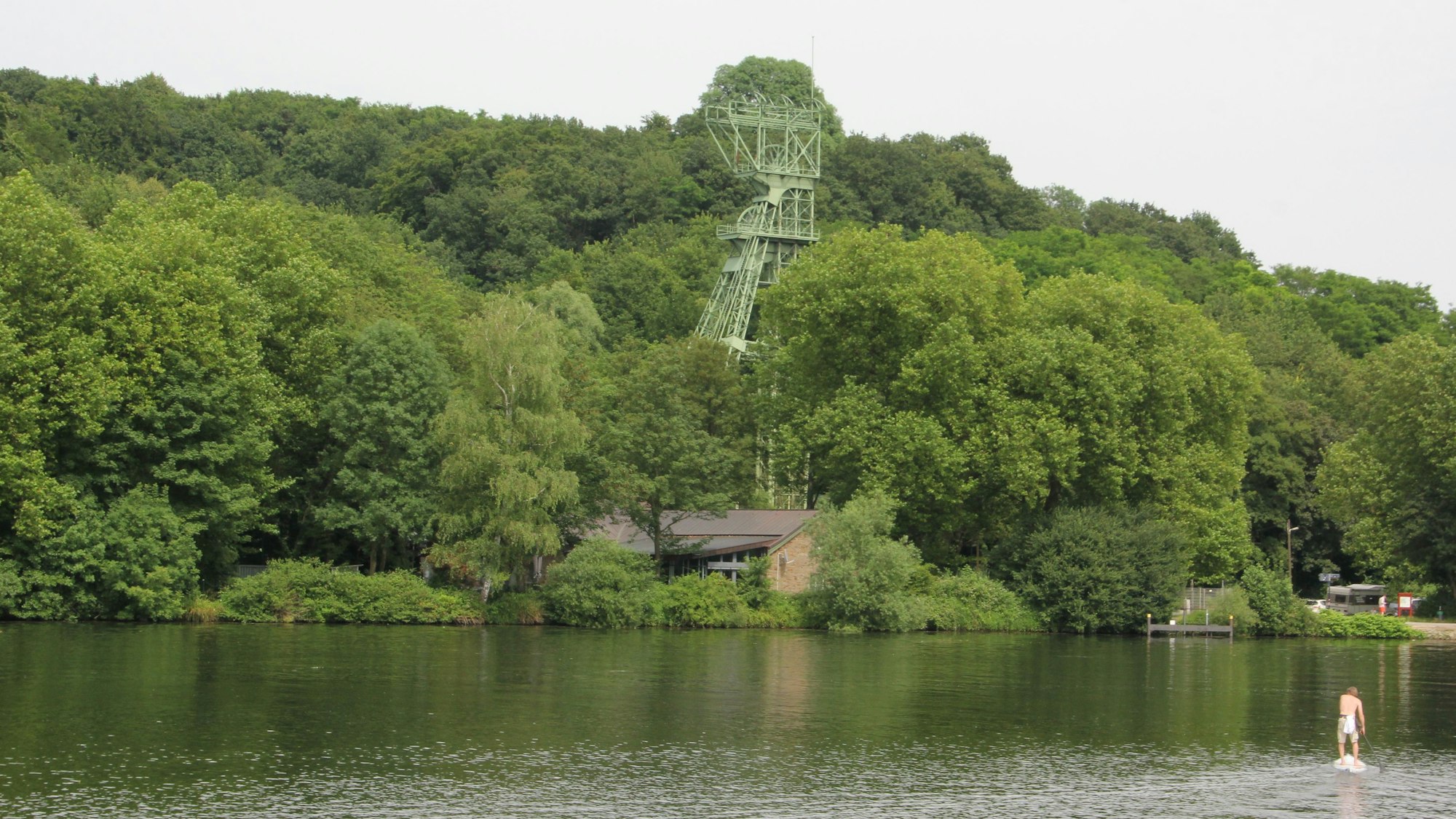 Inmitten von Bäumen steht ein stillgelegter Förderturm am Ufer des Essener Baldeneysess.