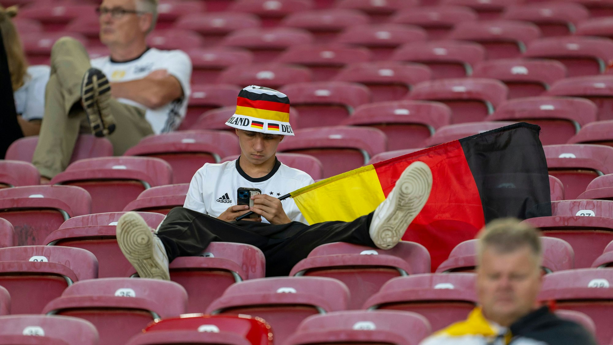 Ein Fan des DFB-Teams schaut nach der Niederlage Deutschlands gegen Spanien im EM-Viertelfinale konsterniert auf sein Smartphone.