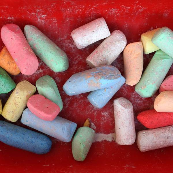 Bunte Straßenmalkreide liegt im Anhänger eines Bobby-Cars.