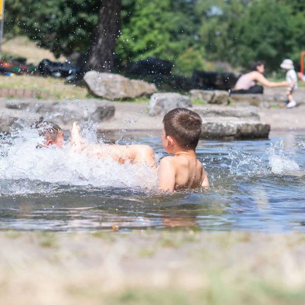 Das Bild zeigt zwei Kindern, die im Wasser plantschen.