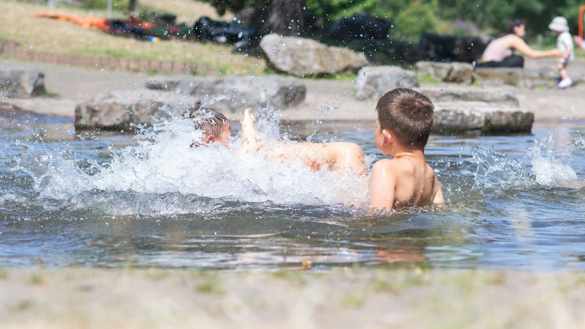 Das Bild zeigt zwei Kindern, die im Wasser plantschen.