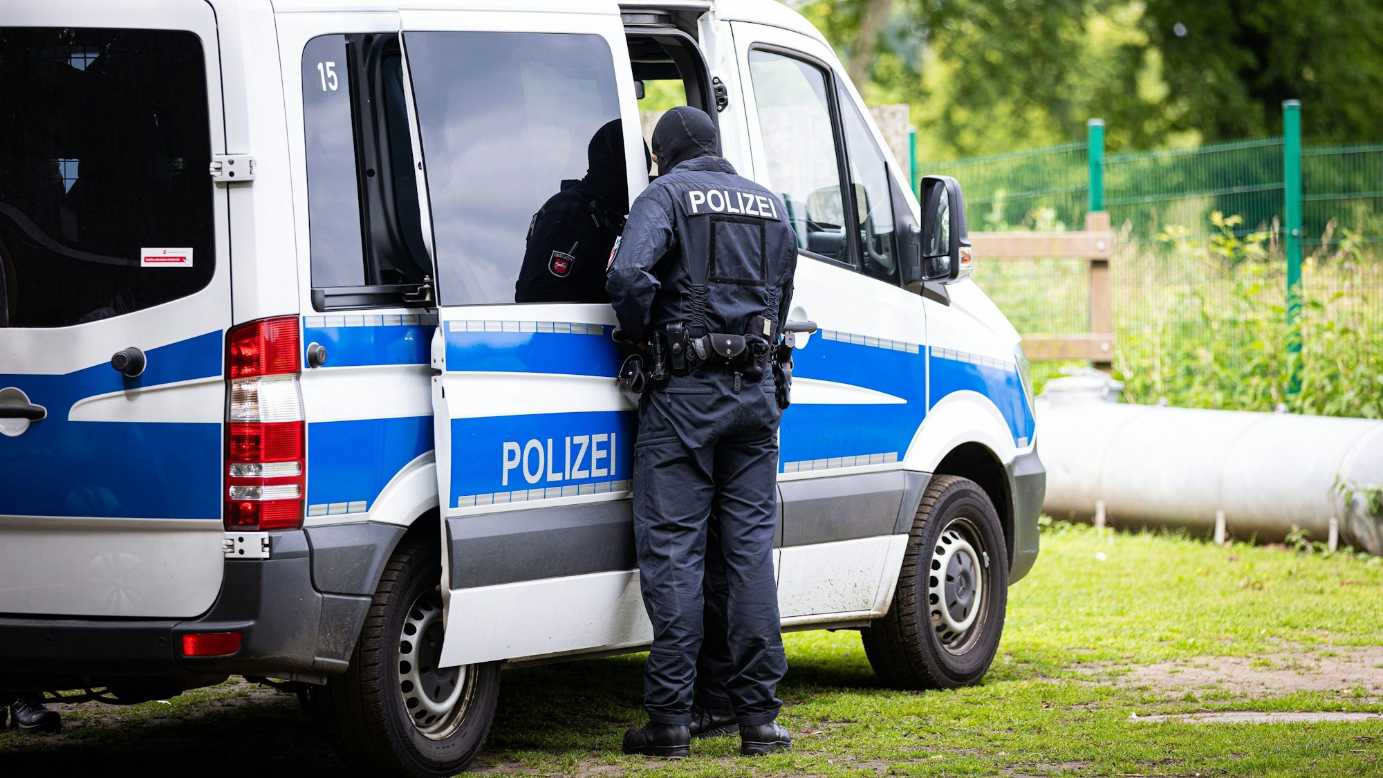 Ein Polizist steht an einem Polizeifahrzeug.