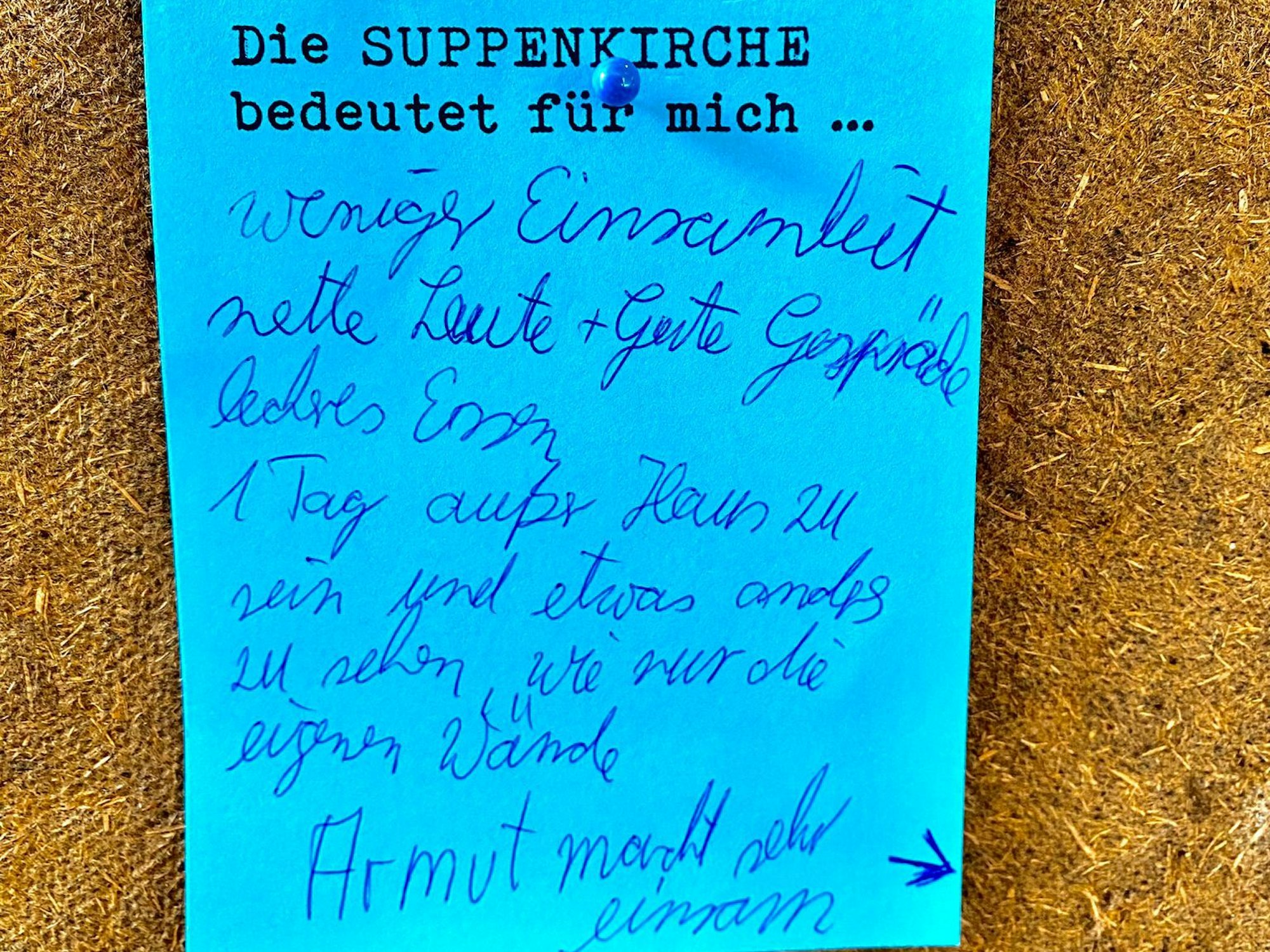 Auf einem blauen Zettel an einer Pinnwand steht, dass Armut sehr einsam macht.