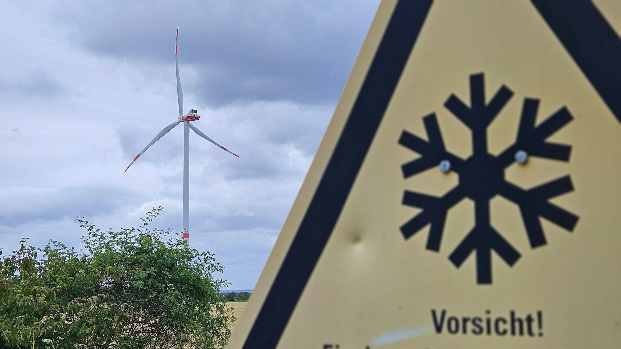 Zu sehen ist ein Schild mit einem Windrad im Hintergrund.