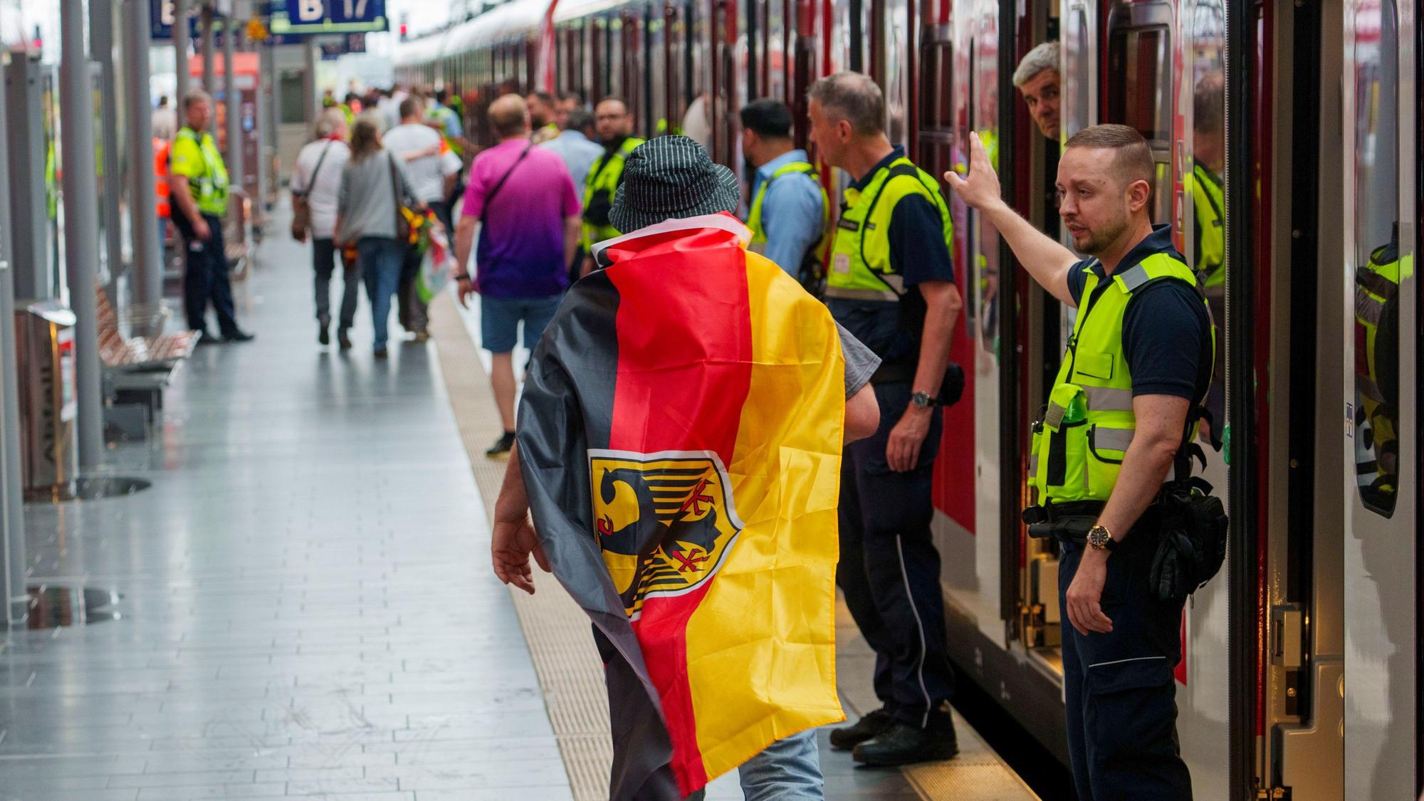 Sicherheitspersonal der Bahn weisst einem deutschen Fan den Weg zu einem freien Abteil, ganz am Ende des Zuges. (Archivbild)