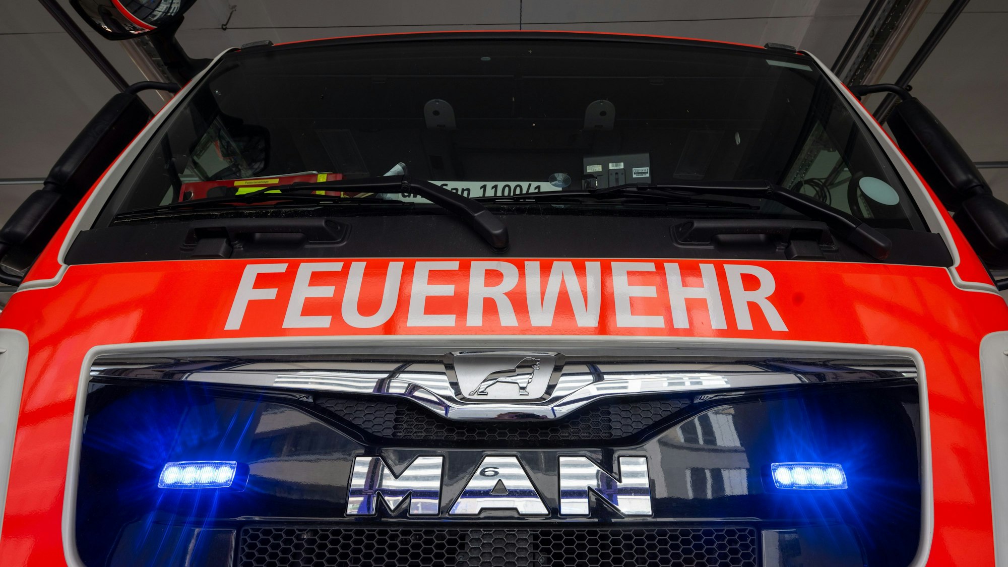 Ein Einsatzwagen der Berliner Feuerwehr mit eingeschaltetem Blaulicht steht in der Fahrzeughalle.