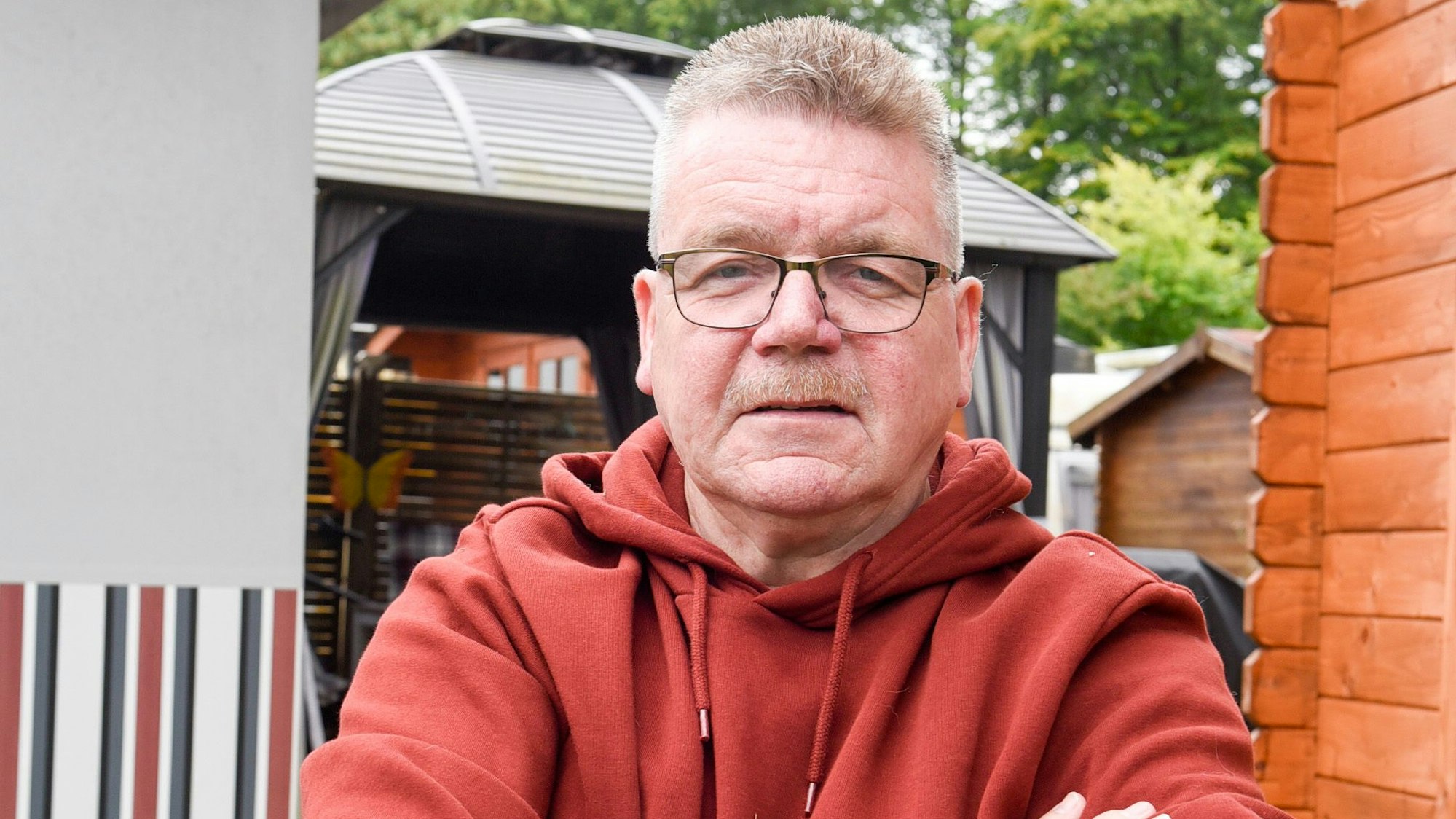 Ein Mann steht neben einer Gartenhütte auf einem Campingplatz.