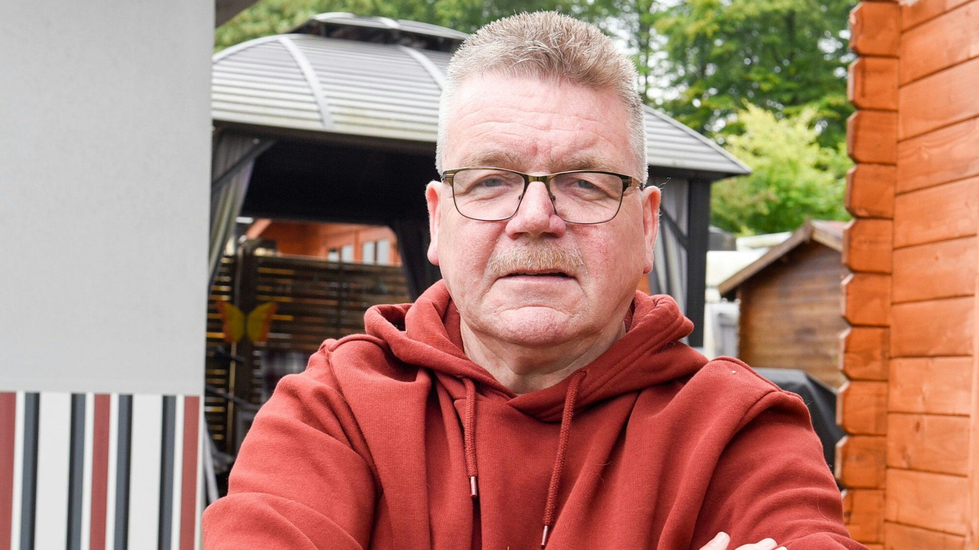 Ein Mann steht neben einer Gartenhütte auf einem Campingplatz.