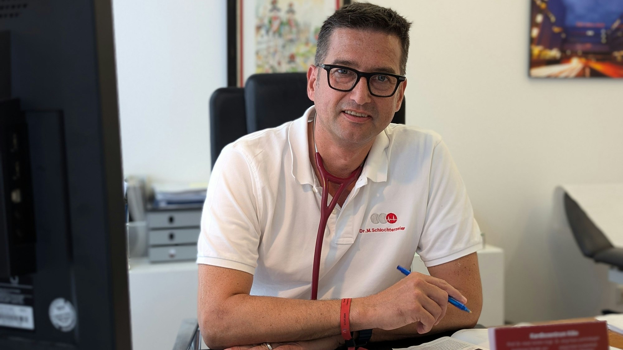 Ein Arzt sitzt an seinem Schreibtisch.