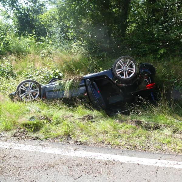Ein Auto liegt am Straßenrand auf dem Dach.