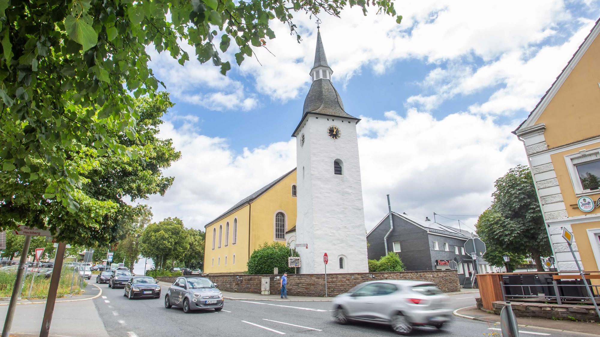 Autos fahren über die Kreuzung, im Hintergrund die evangelische Kirche.