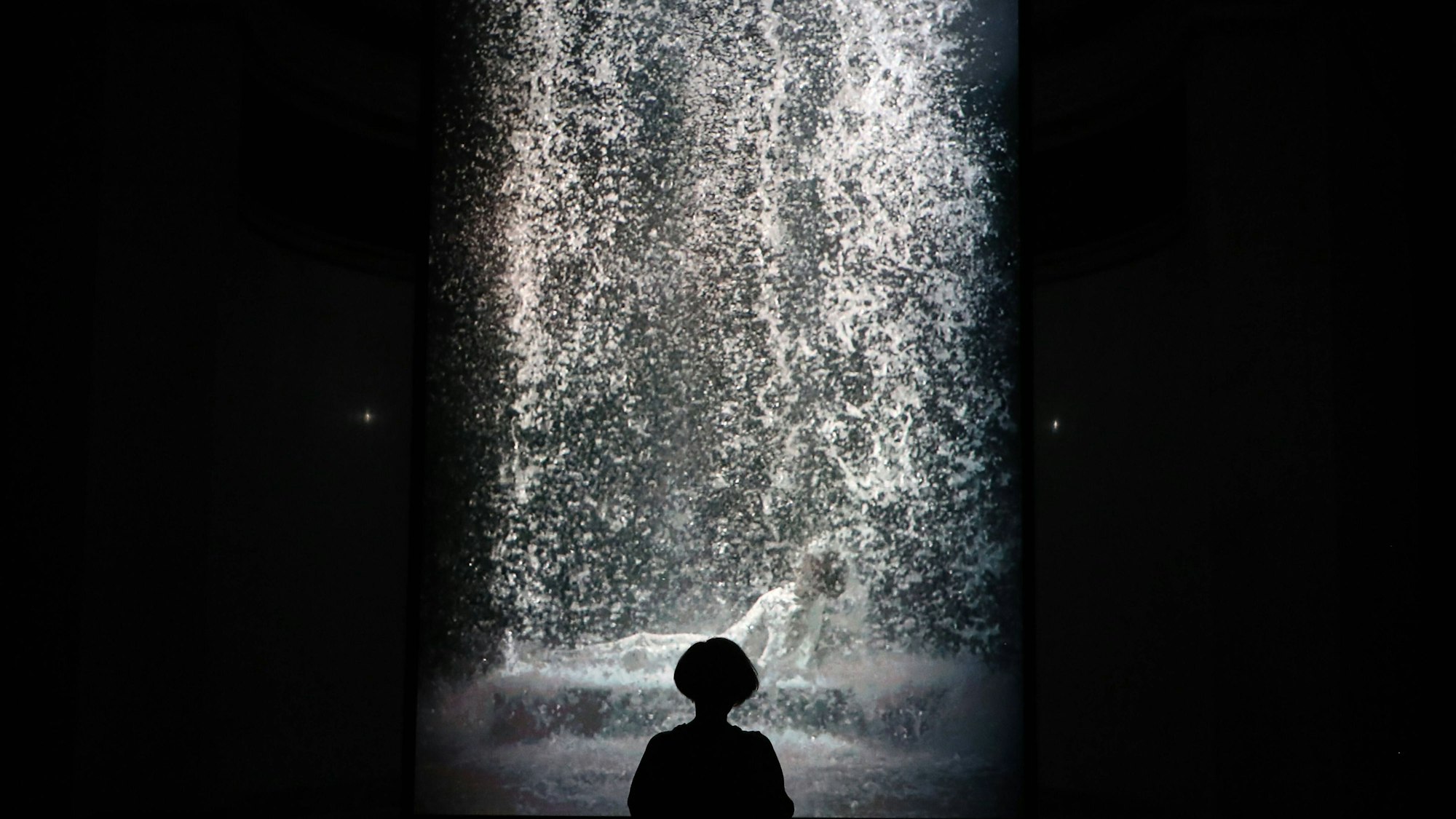 Eine Besucherin betrachtet ein Videokunstwerk von Bill Viola.
