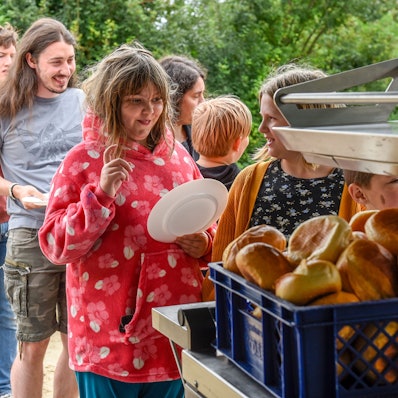 Kinder stehen an, um sich Brötchen zu holen.