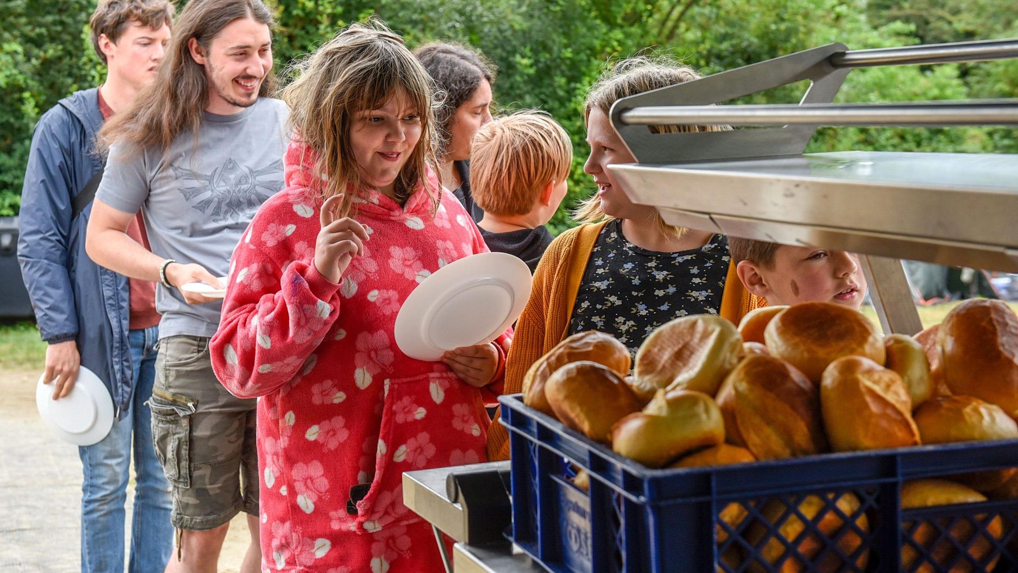 Kinder stehen an, um sich Brötchen zu holen.