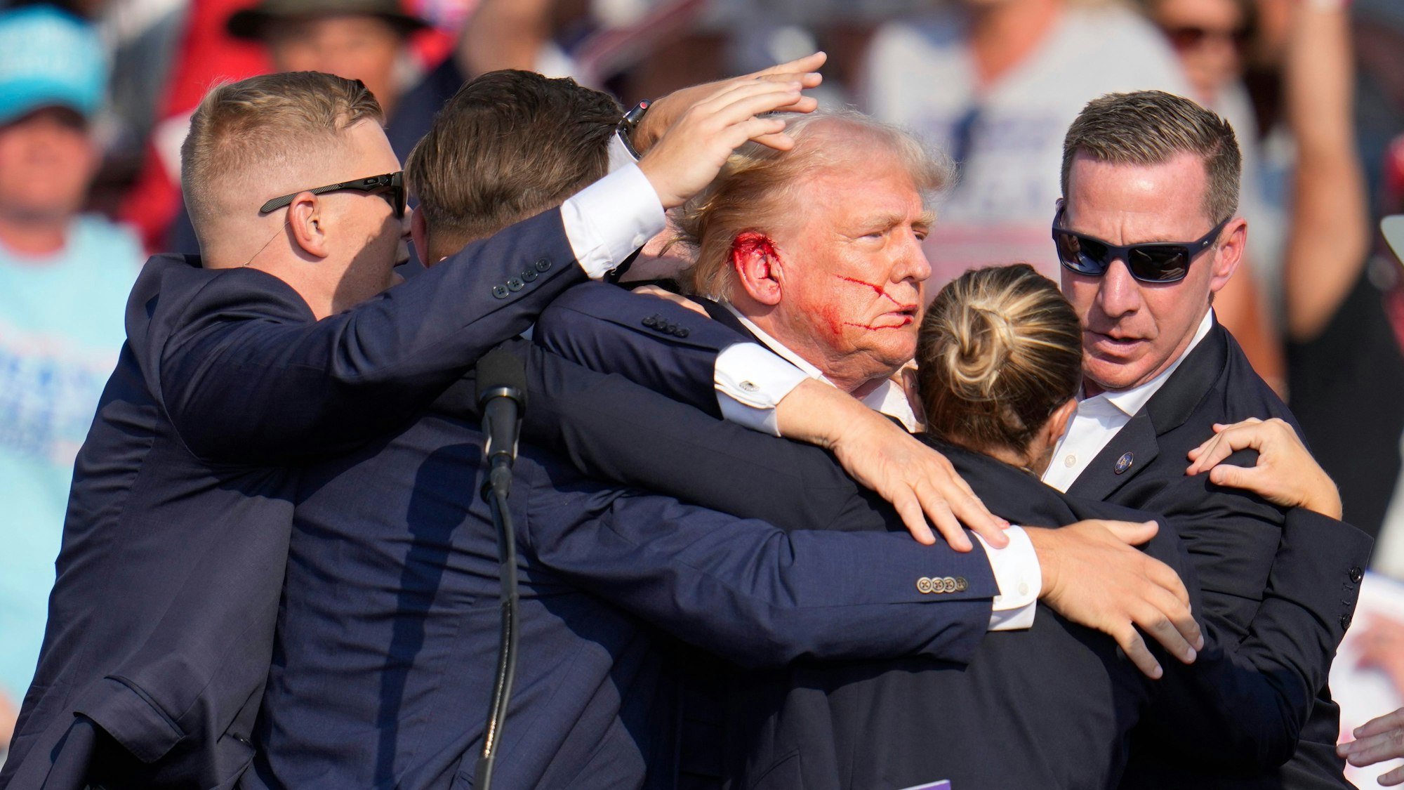 Der republikanische Präsidentschaftsbewerber und frühere US-Präsident Donald Trump wird von Agenten des US-Geheimdienstes Secret Service umringt, als ihm bei einer Wahlkampfveranstaltung von der Bühne geholfen wird.