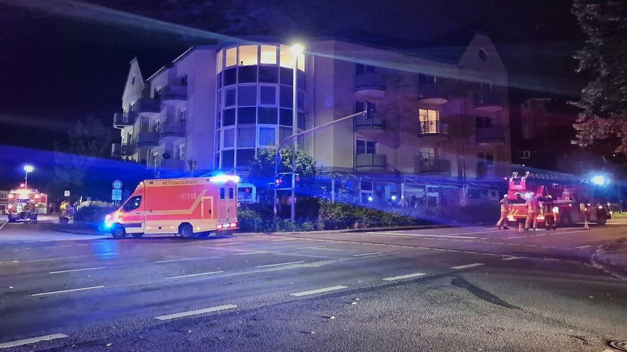 Ein Rettungswagen und Feuerwehrautos stehen nachts vor einem Gebäude.