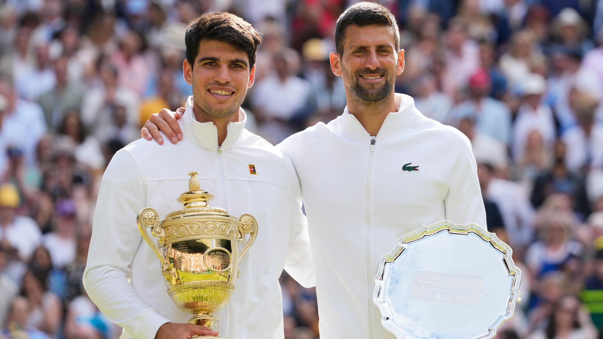 14.07.2024, Großbritannien, London: Tennis: Grand Slam – Wimbledon, ATP-Tour, Einzel, Herren, Finale, Alcaraz (Spanien) – Djokovic (Serbien): Carlos Alcaraz (l) hält seine Trophäe, nachdem er den Novak Djokovic im Finale besiegt hat.