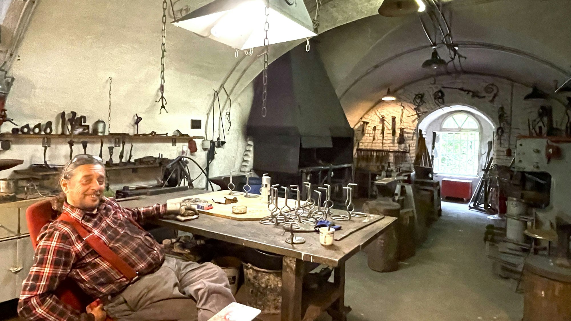 Ein Mann sitzt in einer Schmiederwerkstatt im Zwischenwerk III b in Köln.