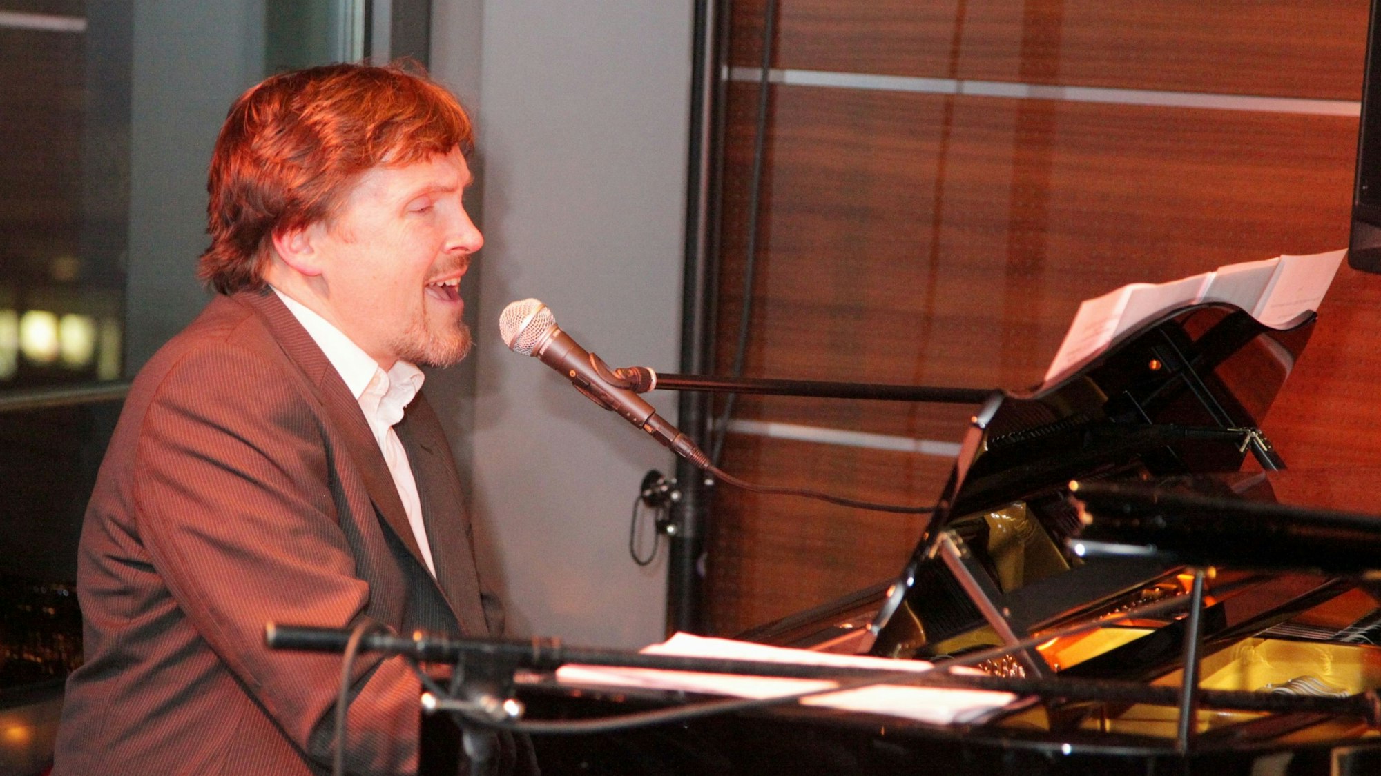 Ein Mann singt und begleitet sich selbst an einem Flügel.