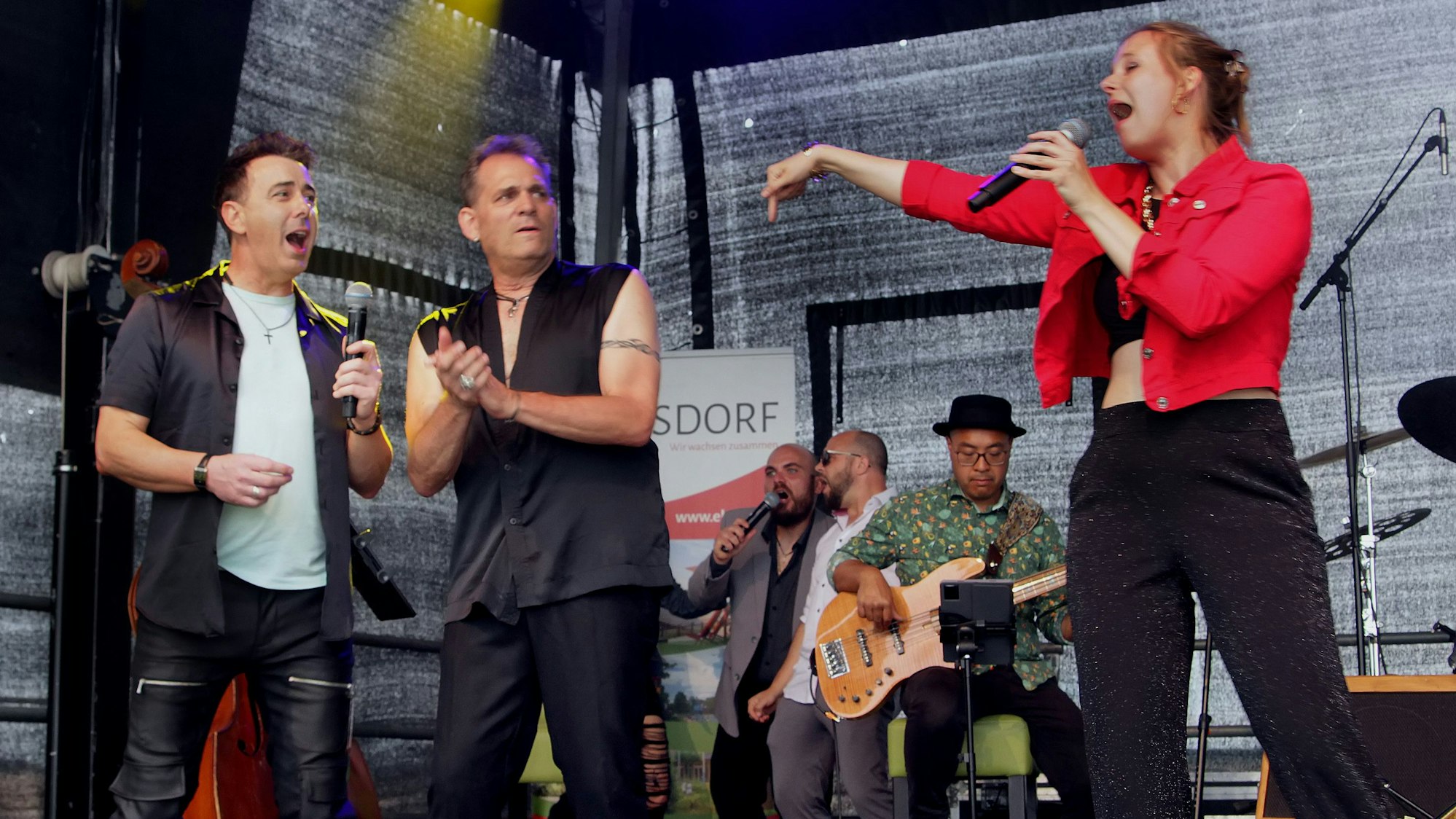 Musiker mit Mikrofon auf einer Bühne.