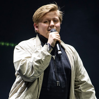 Autot Sebastian „El Hotzo“ Hotz steht auf einer Bühne und spricht in ein Mikrofon.